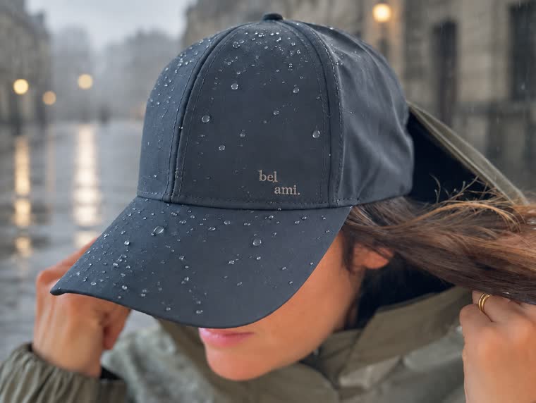 Casquette imperméable portée par une femme, gouttes perlées sur la calotte et la visière