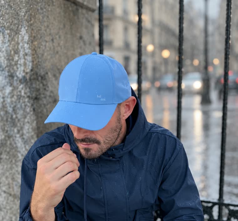 Casquette imperméable bleu clair portée en ville, un jour de pluie